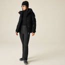 Full-length view of woman wearing a black Dare 2B padded cord jacket with black ski trousers.