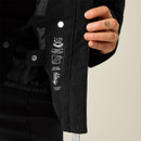 A person holding the black cord jacket showing features like waterproofing, warmth padding, and critically taped seams.