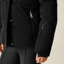 Close-up of a black cord jacket with zip pockets and quilted detailing, worn over black leggings.
