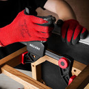 A person wearing red gloves is using a Dekton clamp on a wooden frame with a black surface.