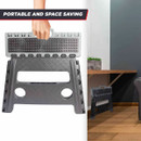 A grey folding step stool with a handle, positioned upright against a wooden table in a modern indoor setting.