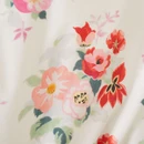 A close-up of a floral fabric featuring pink, red, and green flowers on a light cream background.