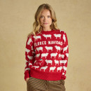 A woman wears a red knit sweater featuring white sheep patterns and ribbed cuffs and hem, paired with checked trousers.