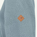 Close-up of light blue textured fleece fabric with small diamond-shaped JP logo badge.