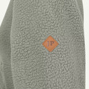 Close-up of sage green textured fleece fabric with small diamond-shaped JP logo badge.