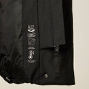 Close-up of black padded jacket showing internal feature icons, adjustable drawcord and fastening details.