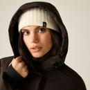 A woman wears a brown jacket with a hood and a cream knitted beanie, highlighting her face and freckles against a neutral background.