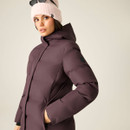 Side view of woman wearing a dark purple padded hooded coat with her hand in the pocket.