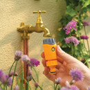 Hozelock non-return valve hose connector being attached to an outdoor garden tap, designed to help prevent water backflow.