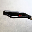 Close-up of a black vacuum handle with a textured grip and a red power switch in the "off" position, set against a blurred, gray background.