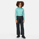 A child with curly hair wears a light blue long-sleeve top and navy trousers, standing on a white background, exuding a casual and confident vibe.