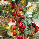 Decorative red berry garland intertwined with evergreen foliage, eucalyptus leaves and warm lights, creating a traditional Christmas display.