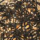 Tangled warm white LED string lights on a wooden background, showing illuminated bulbs and flexible green cable construction.