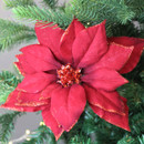 A view of a red poinsettia clip on decoration on a Christmas tree