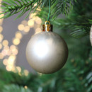 A close up view of a pearl satin bauble hanging from a Christmas Tree.