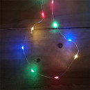 Close-up of multi-colour LED micro wire fairy lights arranged in a circular shape on a wooden surface, with vibrant red, blue, green and warm white LEDs creating a festive glow.