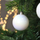 Glossy white iridescent Christmas bauble hanging from an evergreen branch, reflecting soft festive lights for an elegant seasonal display.