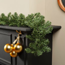 Full artificial pine garland displayed along a mantel shelf with gold baubles, featuring realistic evergreen branches for festive home decoration.