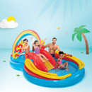 Children playing in a colourful rainbow inflatable water play centre with slide, splash pool and interactive water features.