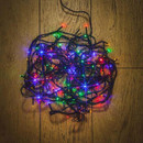 Coiled multicolour LED fairy lights with green wiring arranged on a wooden floor, showing compact storage and vibrant festive illumination.