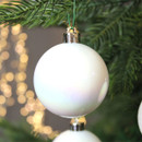 Iridescent white Christmas bauble hanging from an evergreen branch, displaying a subtle pearl sheen and reflective finish for elegant festive décor.