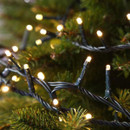 Warm white LED décor tree lights woven through evergreen branches, creating a classic festive glow for Christmas tree decorating.