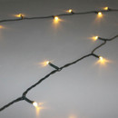 Close-up of warm white LED string lights on dark green wire, showing compact bulbs and flexible cable for easy Christmas decorating.