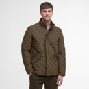 Man wearing a brown quilted jacket with a high collar, hands in pockets. The background is plain white, emphasizing the jacket's texture and style.