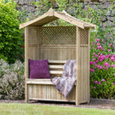 Wooden garden arbour with lattice side panels and built-in bench seating, styled with cushions and a blanket in a landscaped garden.