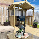 Wooden BBQ shelter on a patio with a barbecue grill and outdoor seating nearby.