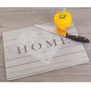 Glass chopping board with “HOME” heart design, shown with a yellow pepper and kitchen knife on a worktop.