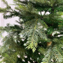 Close-up of lifelike artificial Christmas tree branches with detailed green pine needles and natural-looking foliage for an authentic festive appearance.