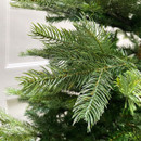 Close-up of evergreen branch tips on an artificial Christmas tree, highlighting lifelike foliage and realistic seasonal styling.