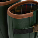 Close-up of the top of green Barbour wellington boots, showing the brown leather-look trim, adjustable strap and buckle, and classic tartan lining inside the shaft.
