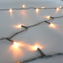 Close-up of antique white LED Christmas lights featuring soft warm-white bulbs on discreet green wiring, highlighting elegant illumination and flexible cable design.