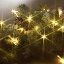 A close-up of decorative greenery adorned with glowing fairy lights, pine cones, and leaves, creating a warm, festive ambiance.