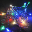 Colourful LED string lights tangled around a small battery box, glowing in blue, green, red, and white against a dark background.