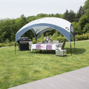 A spacious outdoor dining area under a canopy, featuring a table set with floral decor, chairs, a barbecue grill, and a cooler on green grass.