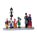 Christmas village carol singers figurine set featuring Victorian-style townspeople gathered beneath a festive street lamp decorated with a Christmas wreath.