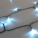 Close-up of ice blue LED Christmas string lights on discreet green wiring, showcasing bright cool-toned bulbs and flexible cable construction.
