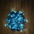 Coiled ice blue LED fairy lights with green cable displayed on a wooden floor, highlighting compact storage and bright LED bulbs.