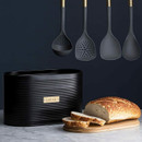 Typhoon black bread bin with bamboo lid displayed alongside sliced bread and matching black kitchen utensils.