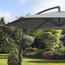 A large, grey patio umbrella stands open in a sunny garden, surrounded by lush greenery and vibrant flowers, creating a peaceful atmosphere.