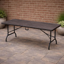 Foldable wood effect plastic table with a slatted surface and metal legs, set on a patio.