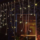 The NOMA 960 Snowing Icicle LED Lights Warm White - 20.6m hanging in a garden
