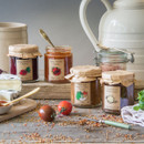 Selection of Edinburgh Preserves chutneys and relishes including beetroot, tomato, onion, and cider chutney displayed with cheese and fresh tomatoes.