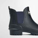 Close-up of the elastic side panel and heel of a navy Barbour Chelsea wellington boot.