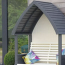 Detail of the arbour’s curved charcoal slatted roof and cream backrest with a colourful cushion, set against a glass wall.