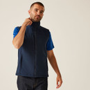 Male model in navy sleeveless softshell vest with full zip, blue t-shirt and jeans, casual workwear layering outfit