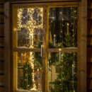 A collection of 10 LED candles hanging from clear wire in a window.